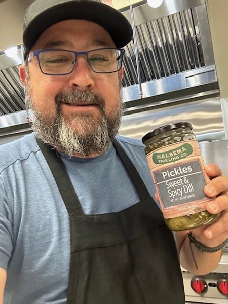 Josh, founder of Halsema Pickling Co., holding a jar of pickles