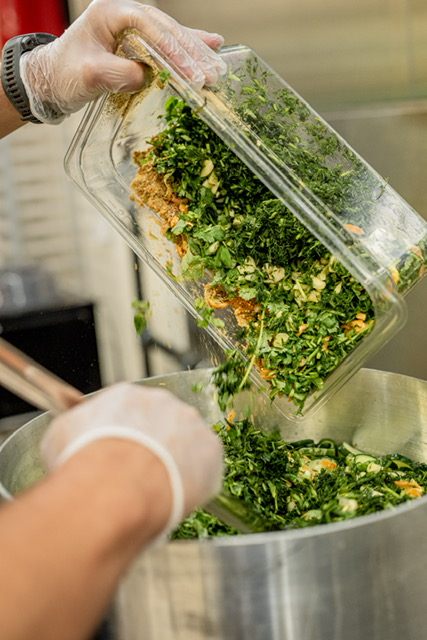 Fresh dill and herbs being mixed into sliced cucumbers